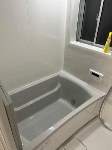 a white bath tub in a bathroom with a window at 高島市一棟貸切可能貸別荘グループファミリーok 大人数でご利用だとお得連泊がお得BBQ可能自転車無料利用可ペット可 駅徒歩10分 in Takashima