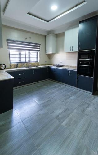 a large kitchen with blue cabinets and a wooden floor at Calini Luxury 2 Bedroom Flat - Sunflower Escape in Abuja