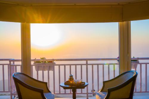a balcony with two chairs and a table on a balcony at ELIVAAS 3BHK Plus Attic Cliffside Villa with Scenic Views in Kasauli