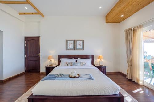 a bedroom with a large bed and a large window at ELIVAAS 3BHK Plus Attic Cliffside Villa with Scenic Views in Kasauli