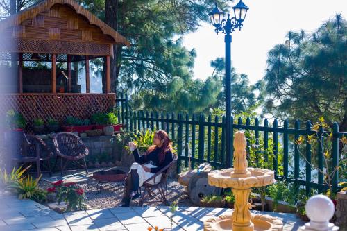 a woman sitting in a chair in a yard at ELIVAAS 3BHK Plus Attic Cliffside Villa with Scenic Views in Kasauli