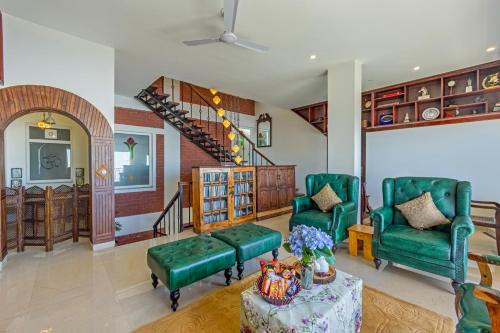 a living room with two green chairs and a table at ELIVAAS 3BHK Plus Attic Cliffside Villa with Scenic Views in Kasauli