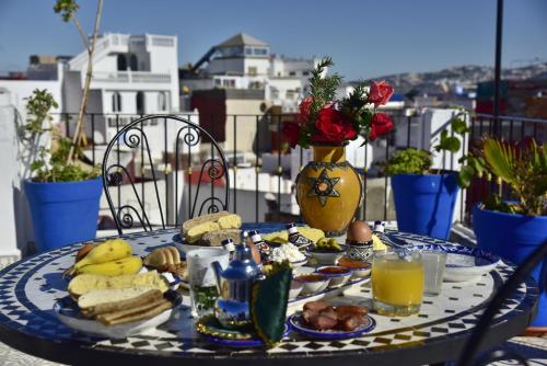 einen blauen Tisch mit Frühstücksspeise und eine Vase Blumen in der Unterkunft Zoco Riad in Tangier