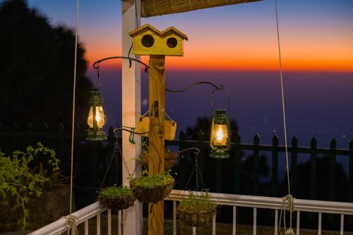 a bird house and lights on a balcony with the sunset at ELIVAAS 3BHK Plus Attic Cliffside Villa with Scenic Views in Kasauli