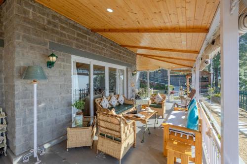 an outdoor patio with chairs and tables and a wooden ceiling at ELIVAAS 3BHK Plus Attic Cliffside Villa with Scenic Views in Kasauli