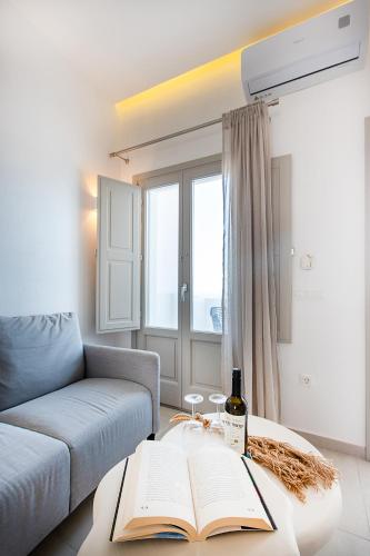 a living room with a couch and a table with a book at Santorini Garden Homes in Mesaria