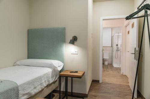 a bedroom with a bed and a table and a bathroom at Pensión María Castaña in Puebla del Brollón