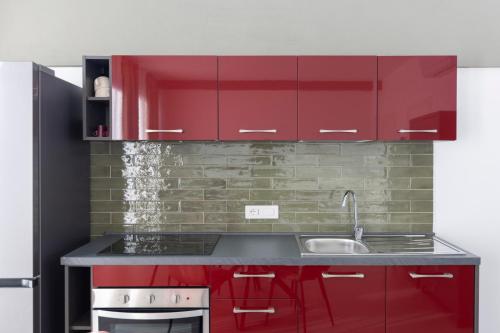 a kitchen with red cabinets and a sink at Associazione Garage24 Aps Ets in Portoferraio