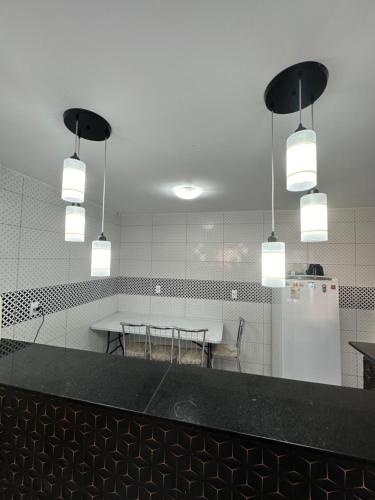una cucina con un tavolo, un frigorifero e luci di Casa em Ipioca a Maceió