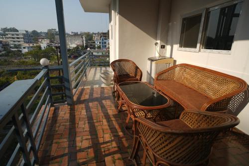 a balcony with wicker chairs and a table on a balcony at Doon Classic A in Rājpur