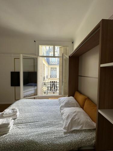 une chambre avec un grand lit et une fenêtre dans l'établissement Au cœur des Champs Élysées, à Paris