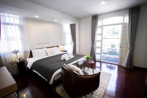 a bedroom with a bed and a chair and a window at Spacious 4-Bedroom Oasis in the Heart of Sukhumvit in Bangkok
