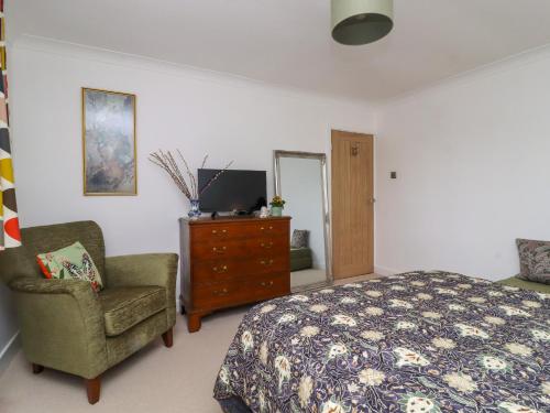 a bedroom with a bed and a chair and a television at Olicana Croft in Ilkley