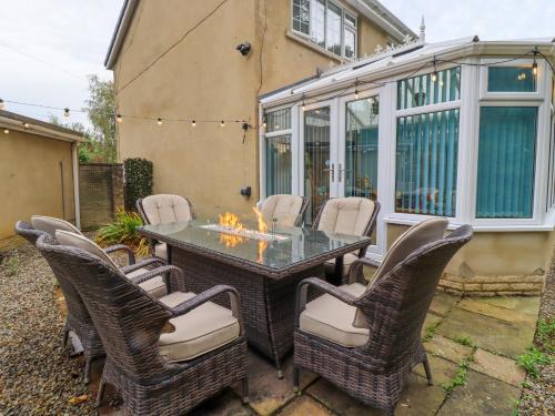 a patio with a table with chairs and a fireplace at Olicana Croft in Ilkley
