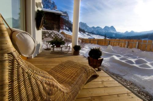 a porch with a bench and a view of the mountains at Family and Wellness Residence Ciasa Antersies in San Cassiano