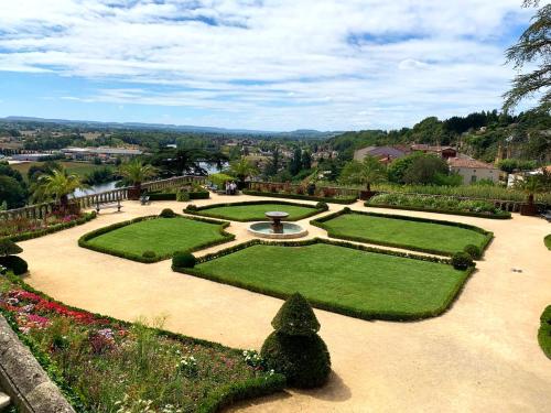 a garden with a fountain and grass and bushes at Studio Preto - Confort moderne - Terrasse - Parking gratuit - Non fumeur in Fumel