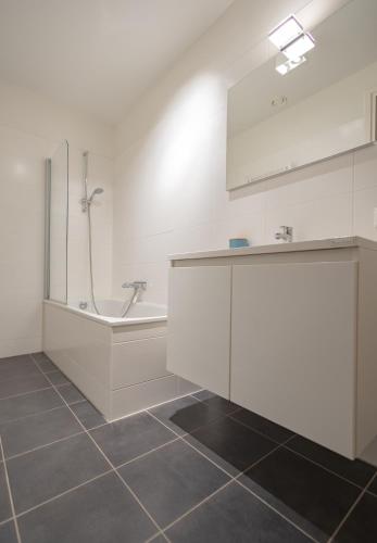 a bathroom with a shower and a sink and a tub at Duinhof VI 6 in Cadzand