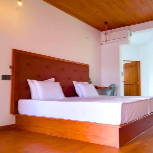 a bedroom with a large bed with a wooden headboard at Thusara Guesthouse in Mirissa