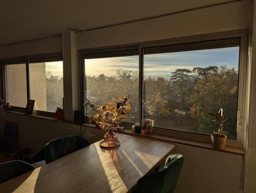 une table de salle à manger avec un vase de fleurs dessus dans l'établissement T3 lumineux avec vue panoramique - Point du Jour, à Lyon