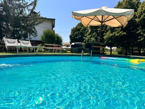a large blue swimming pool with an umbrella and an umbrella at casa nonna Rica in Calcio