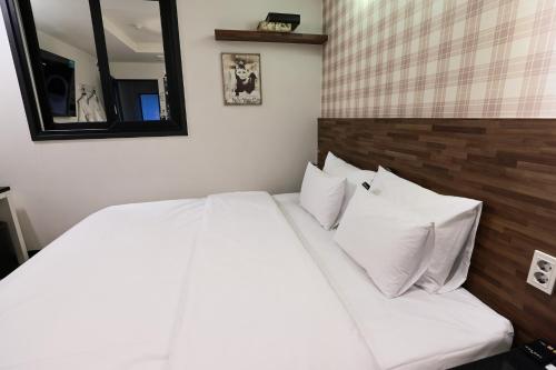 a white bed with two pillows in a bedroom at Hotel Kkuljam Stay in Jinju