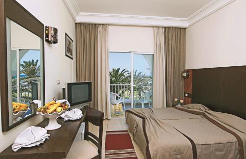 Habitación de hotel con cama y escritorio con TV. en El Mehdi Beach Resort ex Primasol El Mehdi, en Mahdia