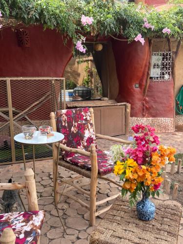 a patio with a table and a chair and flowers at Riad Beldi by MaHa in Oulad Teima