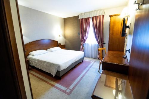 a bedroom with a bed and a desk and a window at Hotel Rendez Vous in Châtillon