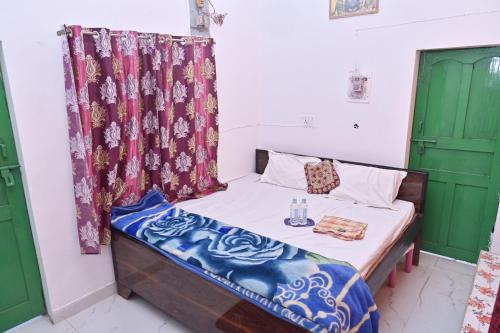 un piccolo letto in una stanza con porte verdi di Luv Kush Homestay Ayodhya call now- 7,5,6,5,9,2,4,8,4,4 a Ayodhya