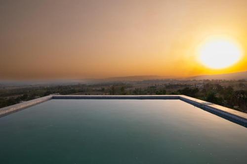 a swimming pool with the sunset in the background at Uday Sunset View Villas By Royal Collection Hotels in Nainital