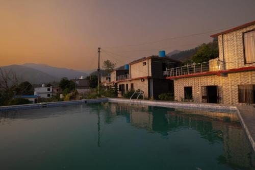 a large swimming pool in front of a house at Uday Sunset View Villas By Royal Collection Hotels in Nainital
