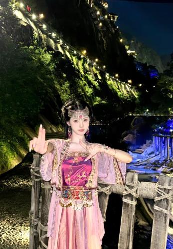 a woman in a pink dress standing on a bridge at Wangxian Valley Qingchuanxingguan - Wangxian Valley Scenic Area in Jiangcun