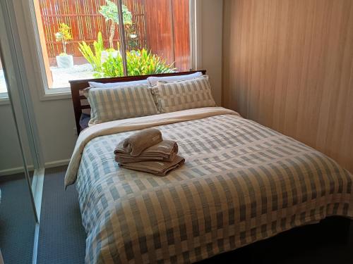 a bed with a towel on it with a window at Romanic Garden View 1 bed Apartment with ocean views at Stanwell Tops in Stanwell Park