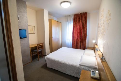 a hotel room with a bed and a desk and a television at Hotel Rendez Vous in Châtillon