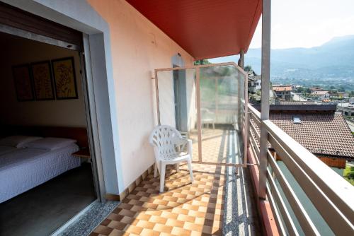 a white chair sitting on a balcony with a bed at Hotel Rendez Vous in Châtillon