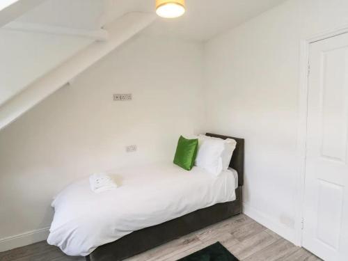 a white bed with a green pillow on it at Pannett Park Rooms in Whitby