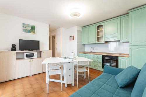 a kitchen with green cabinets and a blue couch at C22 Beachfront Villa - SPA BATH, POOL, PRIVATE BEACH, PARKING FREE in Marina dʼAndora