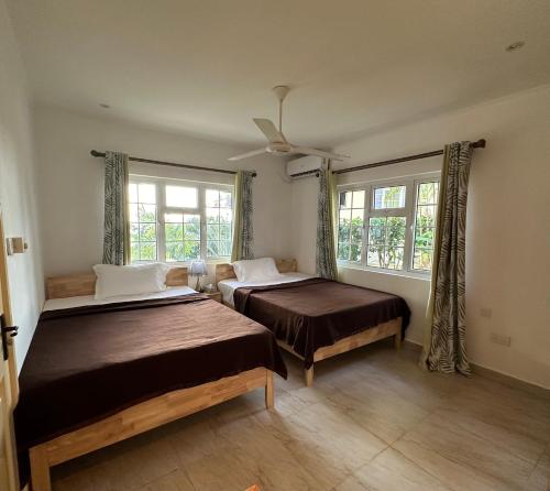 two beds in a room with two windows at Spas Villas La Villa in Victoria