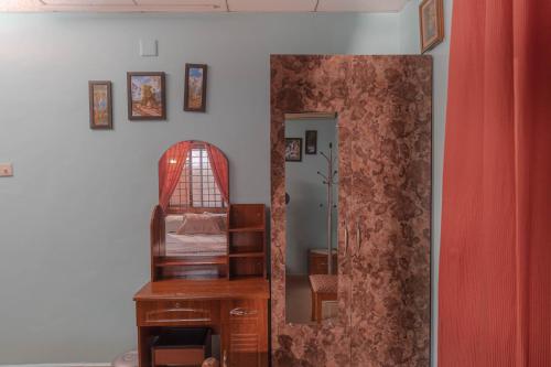 a mirror in a room with a bed and a chair at UDUPI HOMESTAY- White House in Udupi