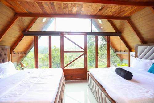 two beds in a room with a large window at 3Acres Sneha Villa in Haputale