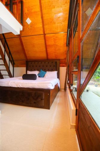 a bed in a room with a wooden ceiling at 3Acres Sneha Villa in Haputale