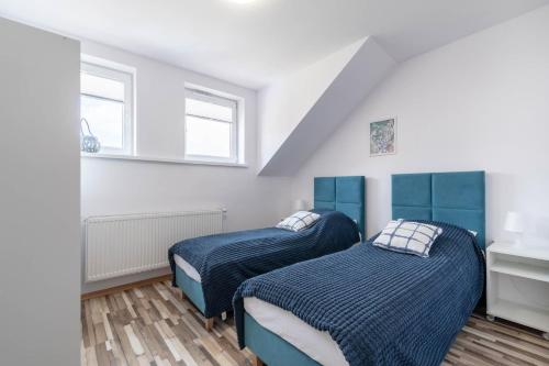 two beds in a room with two windows at Apartament Mąki Gram in Złocieniec