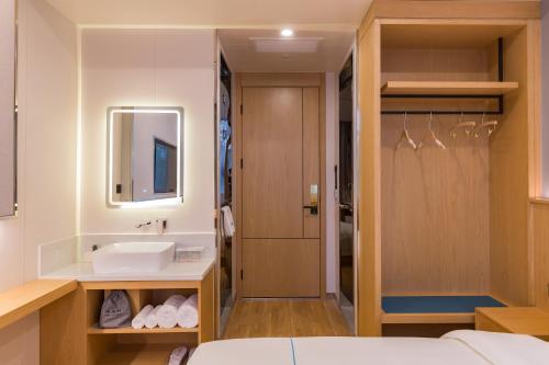 a bathroom with a sink and a mirror at Dequan Luxury Hotel Communication University of China Branch Coffee, fruits, snacks, a gym and a laundry room are provided for free in the lobby in Beijing