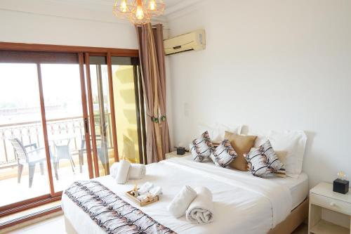 ein Schlafzimmer mit einem großen weißen Bett und einem Balkon in der Unterkunft Cosy cocon au coeur de Gueliz-Parking gratuit in Marrakesch