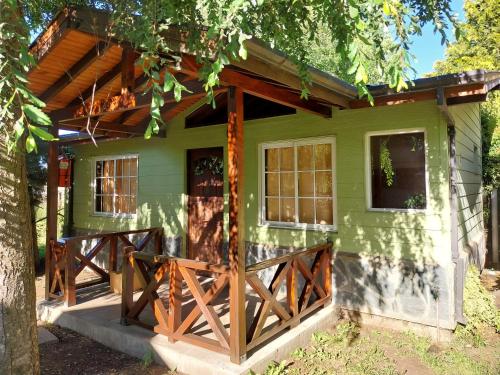 a green house with a wooden porch at El Bolsón Cabaña Arrayanes para 2 in El Bolsón