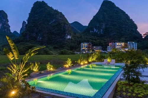 a resort pool with mountains in the background at Yangshuo 1Q84 Tree Hotel in Yangshuo