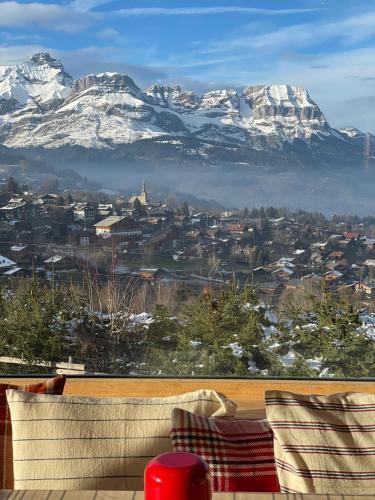 a view of a city with snow covered mountains at Hôtel Le Caprice Des Neiges Combloux in Combloux
