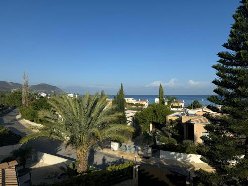 a view of a city with a palm tree and the ocean at Beautiful Villa in Latchi in the best location! in Neo Chorio