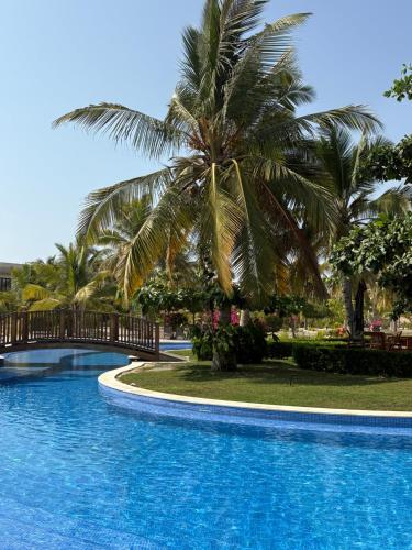 a palm tree sitting next to a swimming pool at Villa Davelin, Hawana Salalah in Salalah