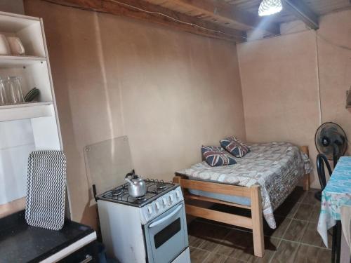 a small room with a stove and a bed at Macrigaluma Luna solo con seña in Barra del Chuy